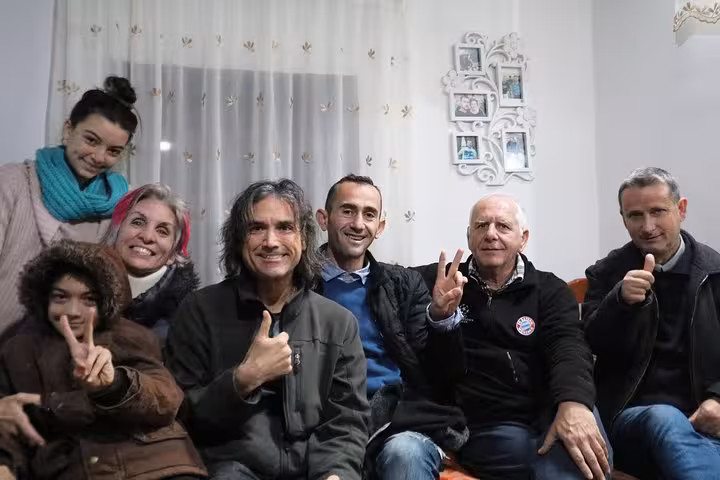Group of people smiling and gesturing thumbs up, enjoying a communal moment at a traditional Albanian cooking class.