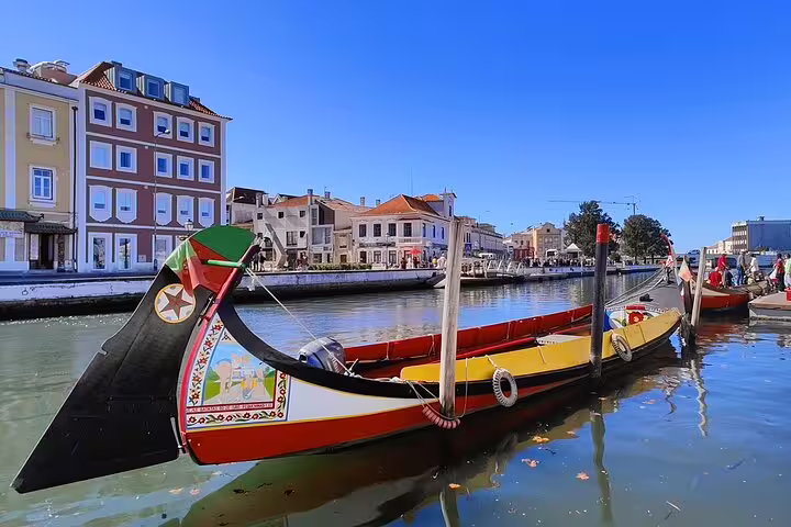 Colorful traditional boat on Aveiro canal during a private transfer tour from Lisbon to Porto, showcasing picturesque Portuguese architecture.
