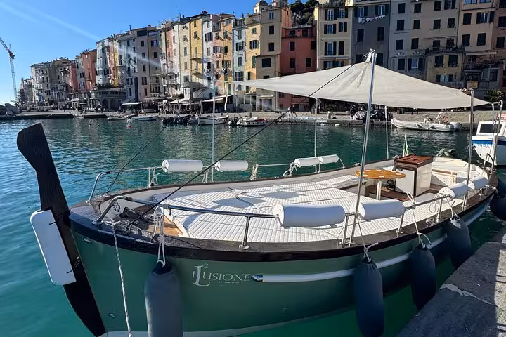 Traditional boat docked in Cinque Terre's harbor with colorful village backdrop and serene turquoise waters.