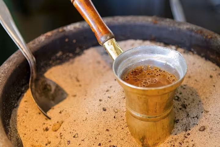 Traditional Greek coffee brewing in hot sand, showcasing authentic preparation methods in Athens.