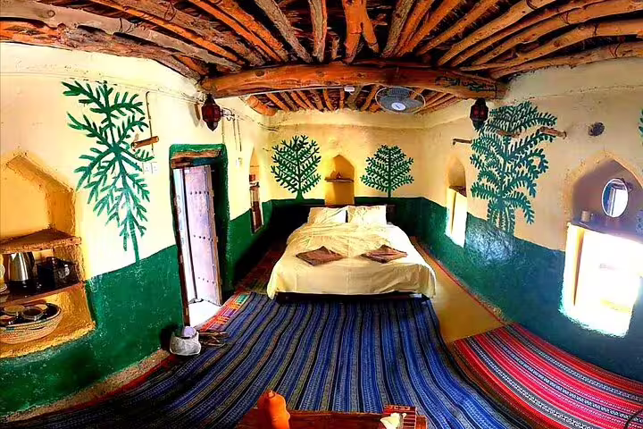 Traditional Omani bedroom with wall art and woven rugs on a Jebel Akhdar Al Suwjara Village private tour.