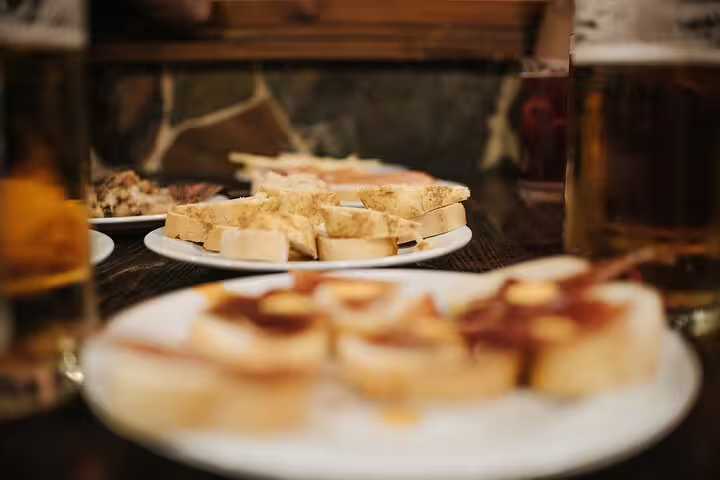 Plates of traditional Spanish tapas and glasses of beer on a table during a lively Madrid tapas tour experience.