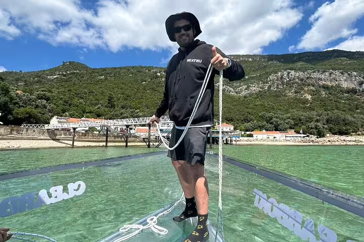 Guide standing on a transparent boat deck near Sesimbra, ready for a coastal adventure.