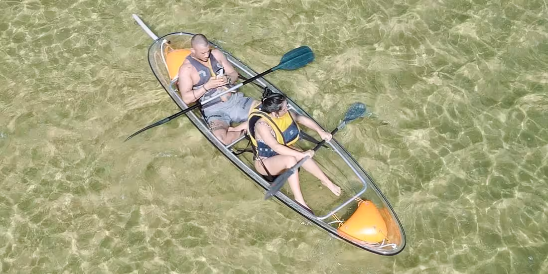 Top-down view of two guests in a transparent kayak on crystal-clear water, ideal for a 4-hour kayak rental