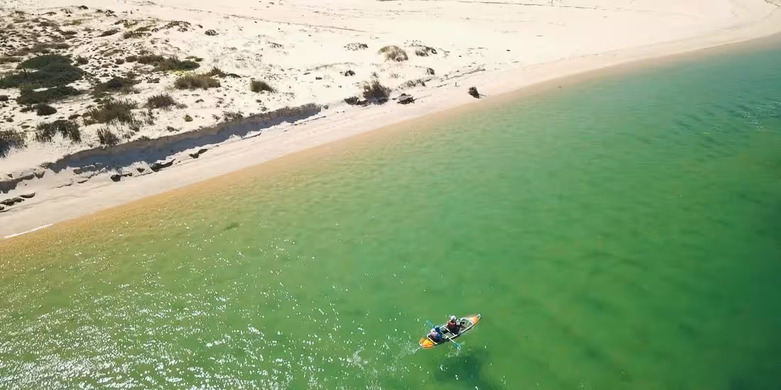 Aerial view of a clear kayak near a white sand beach on turquoise water, perfect for a 2-hour rental experience