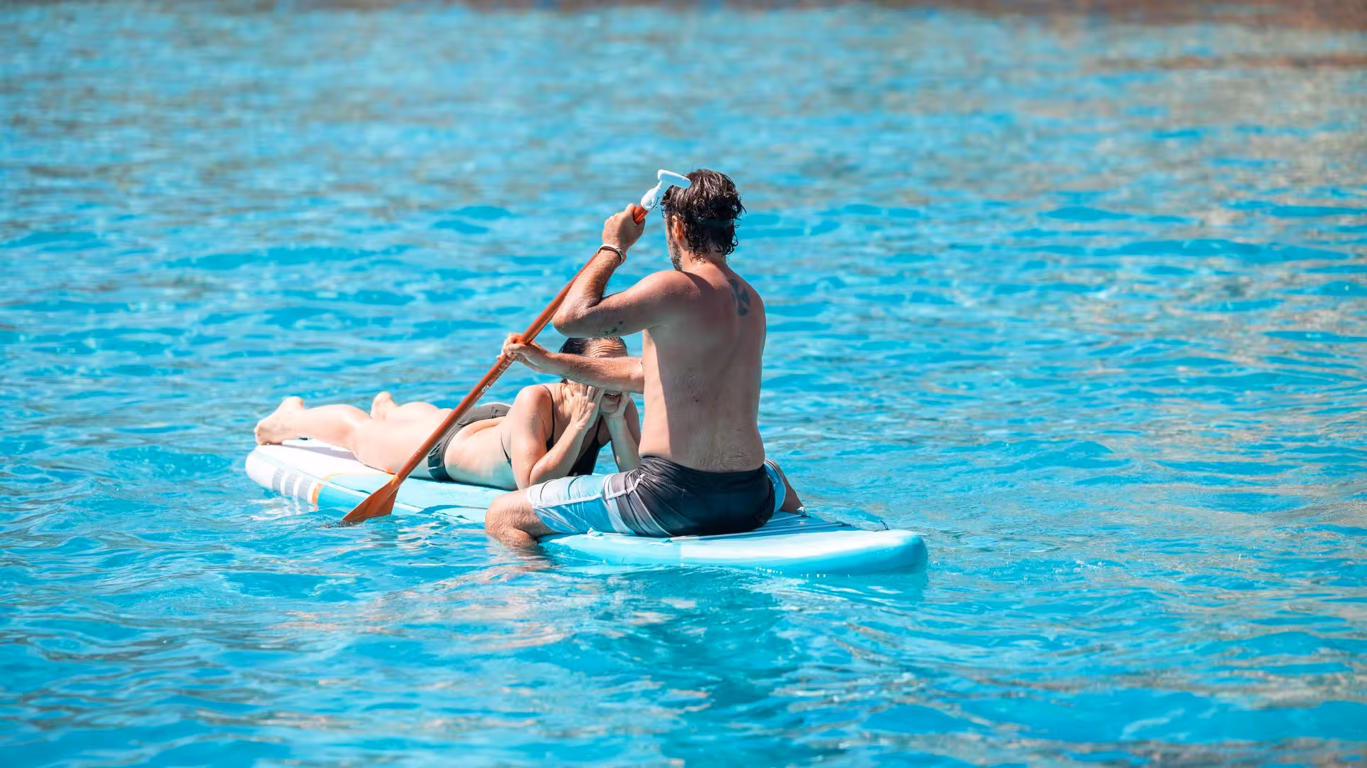 Couple enjoying a paddle on a turquoise sea during a dinghy tour from Trapani to Favignana and Levanzo.