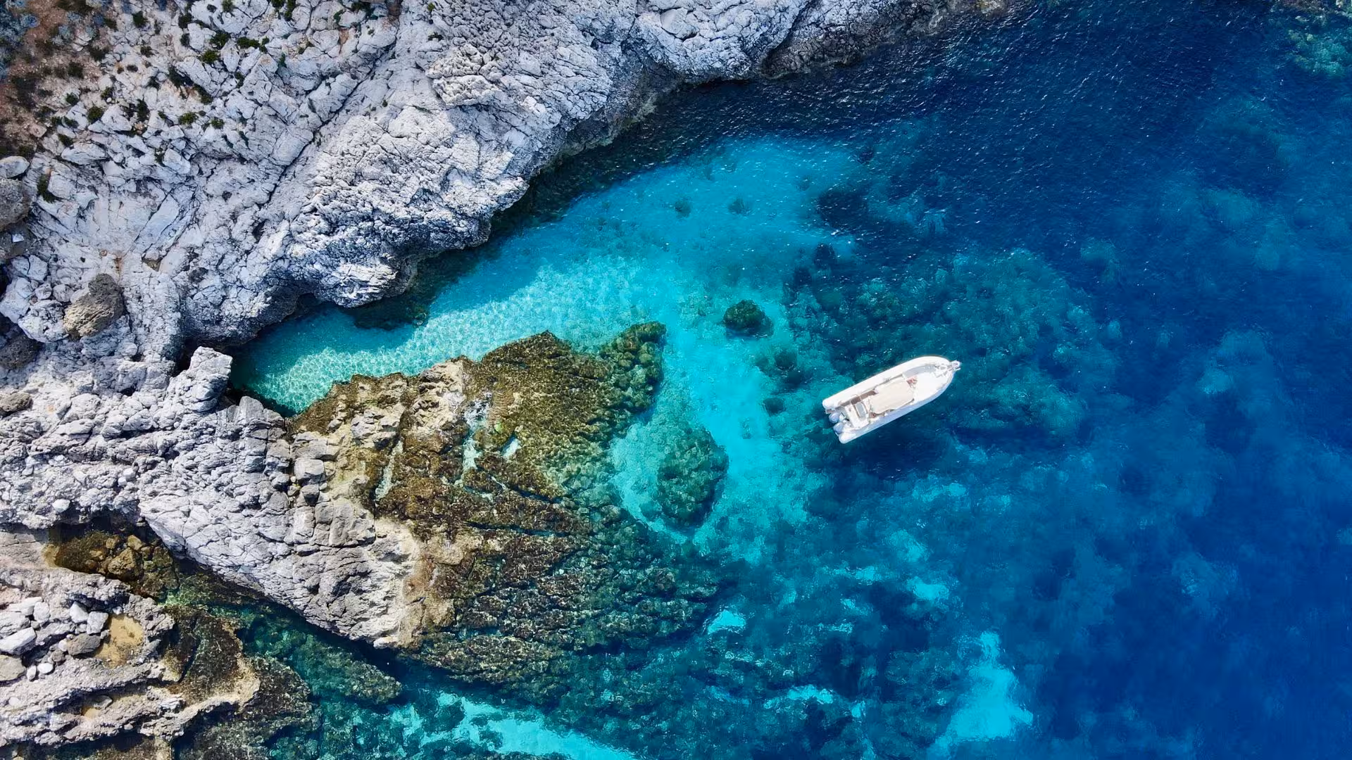 Scenic aerial view of a secluded cove with a dinghy moored in blue waters during a Trapani island tour.