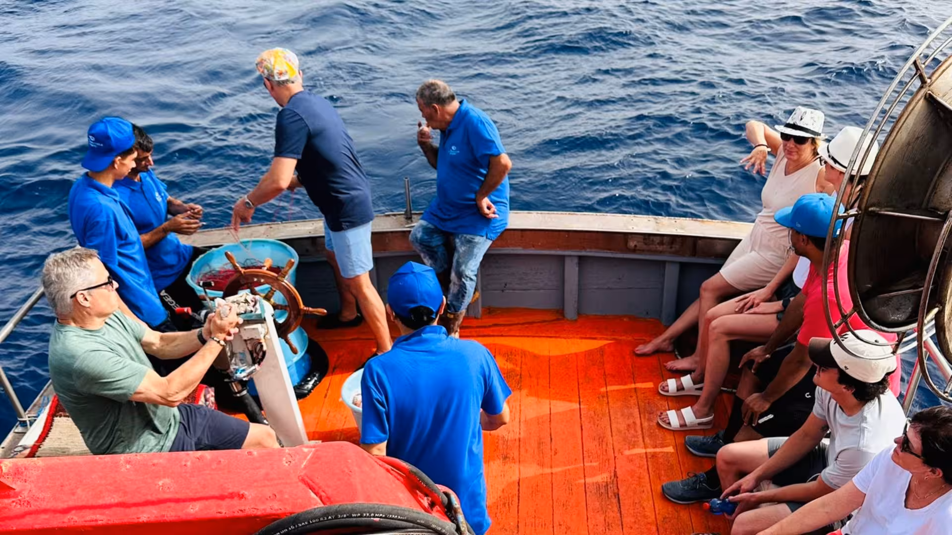 Group of tourists on a boat enjoying Trapani fishing tour in the Egadi Islands, interacting and relaxing on deck.