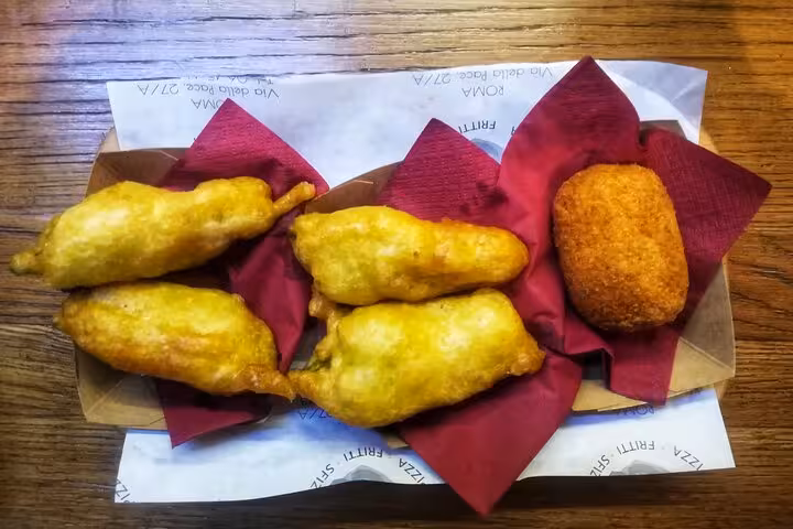 Platter of golden fried zucchini flowers and a croquette served on a Trastevere food tour.