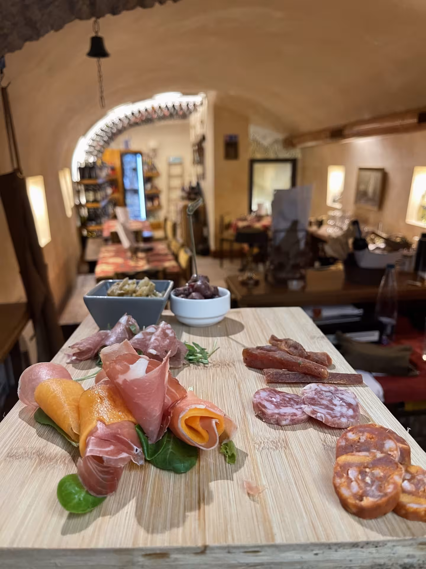 Rustic Italian charcuterie board with prosciutto and salami in a cozy Trastevere wine cellar setting.