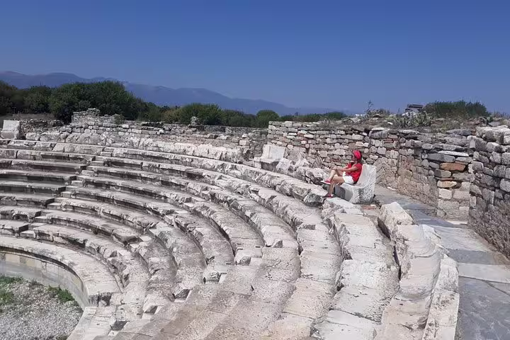 Traveler sitting on Aphrodisias amphitheater stone seats, included in Pamukkale Aphrodisias Ephesus two-day trip