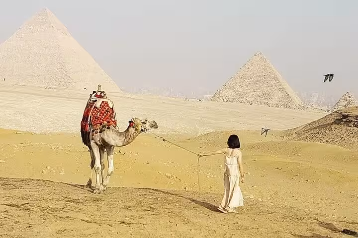 Traveler with camel in Giza desert with Great Pyramids backdrop on Cairo private tour and photo stop