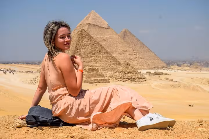 Traveler sitting in Giza desert with Great Pyramids behind on Cairo full-day customized tour adventure