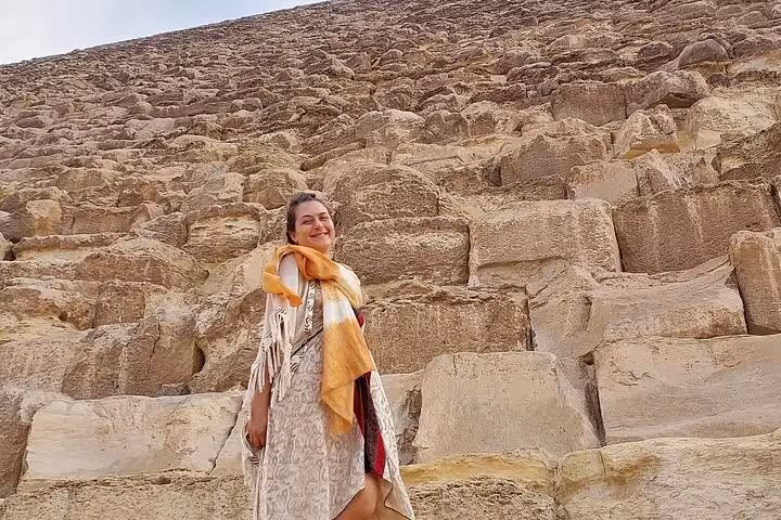 Traveler standing by the Great Pyramid of Giza stones on a private full-day Cairo tour with guide