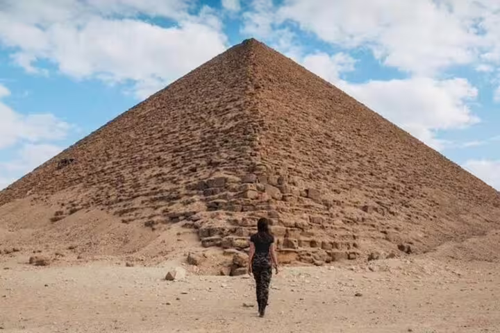 Traveler walking toward the Great Pyramid of Giza under blue sky, featured on Cairo 3-day highlights tour