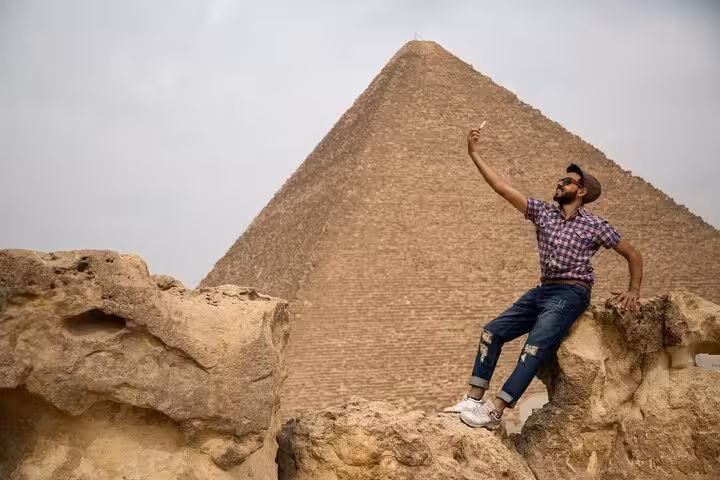 Traveler posing by the Great Pyramid of Giza on a Cairo full-day customized tour adventure with camel ride
