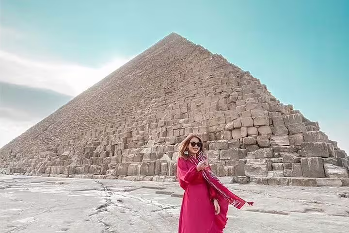 Traveler in pink beside the Great Pyramid of Giza on a private guided tour with Grand Egyptian Museum visit
