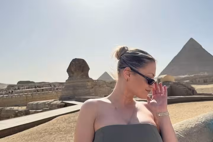 Traveler posing by the Great Sphinx with Giza Pyramids on a half-day private guided tour in Cairo, Egypt