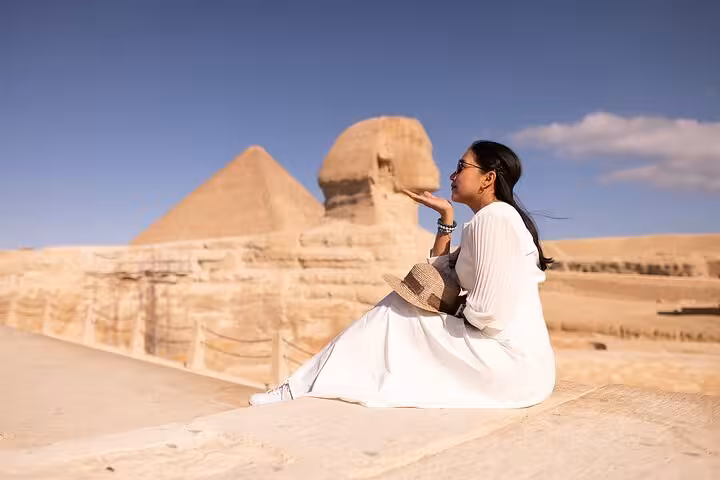 Traveler posing by the Great Sphinx with Giza Pyramid backdrop on VIP Giza & GEM tour in Cairo, Egypt