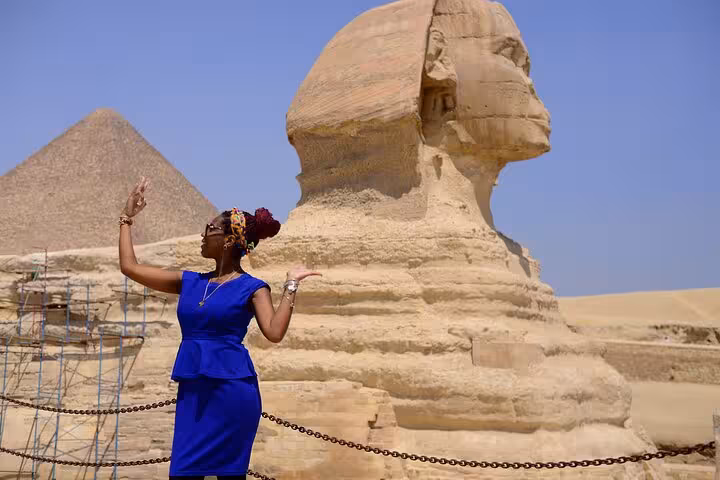 Traveler posing by the Great Sphinx with a Giza pyramid behind, guided Giza Pyramids tour Cairo Egypt