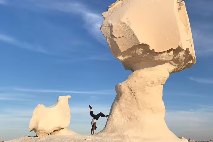 Traveler does a handstand beside iconic mushroom rock in Egypt’s White Desert on a private Bahariya tour