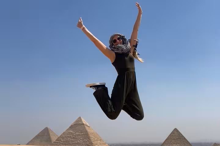 Traveler jumping at Giza Pyramids on private tour with ATV desert ride and Great Sphinx visit in Cairo