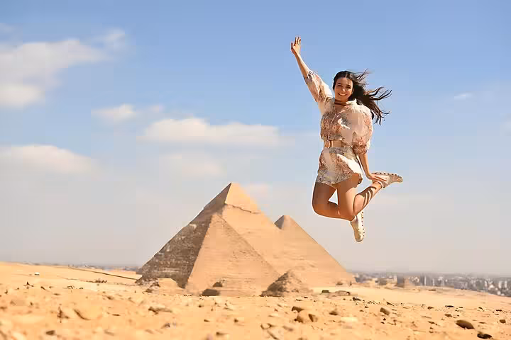 Traveler jumping with the Giza pyramids behind on a Cairo day trip pyramids, Sakkara & Memphis tour with lunch