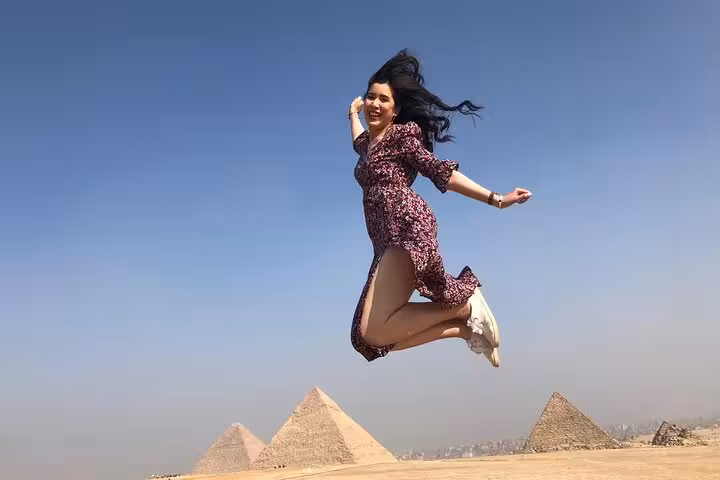 Traveler jumping with the Giza Pyramids behind on a private guided tour in Cairo with hotel pickup