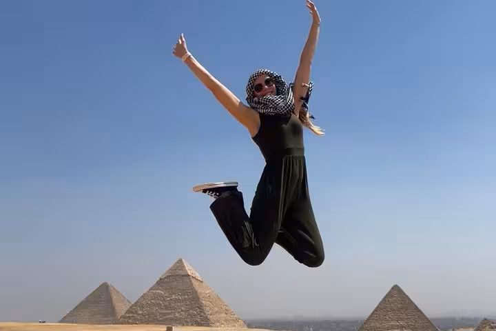 Traveler jumping with Giza pyramids in background on a private Giza tour with panoramic desert views