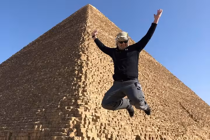 Traveler jumping near the Great Pyramid of Giza on a private pyramids tour in Cairo with lunch and camel ride