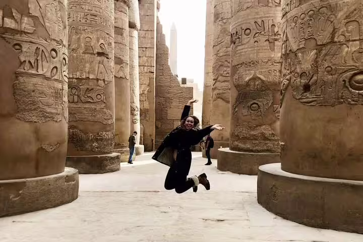 Traveler jumping among Karnak Temple columns in Luxor on East Bank Nile tour, Egypt day trip highlights