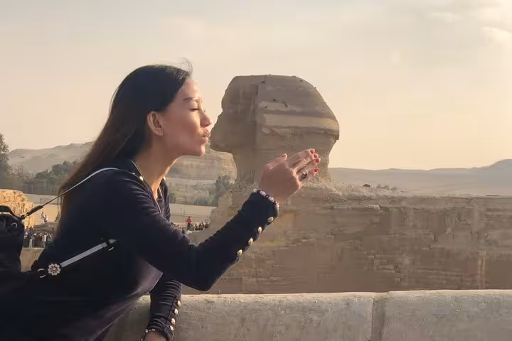 Traveler posing to kiss the Great Sphinx at Giza during private pyramids and Sphinx tour in Cairo