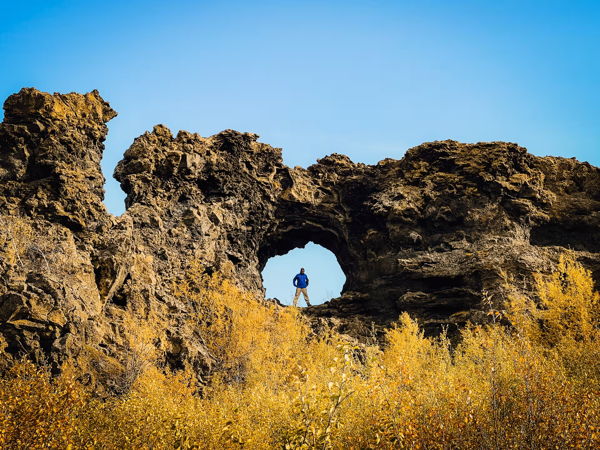 Traveler standing in a lava rock arch near Lake Mývatn, North Iceland adventure from Akureyri cruise port