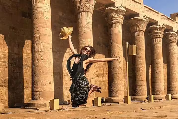 Traveler jumping by carved columns at Luxor Temple, Egypt on 12-day Cairo Luxor Aswan Petra tour