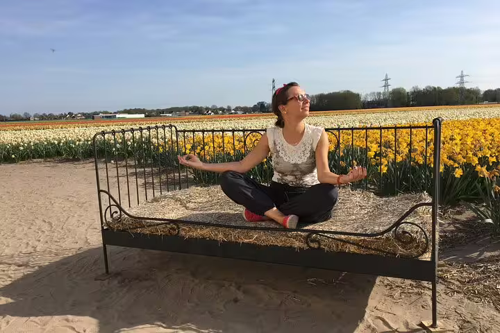 Traveler meditating on a hay bed beside yellow tulip fields, relaxing on Your Own Holland e-bike tour