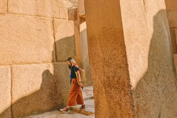 Traveler walking between massive stone walls at Memphis ruins on Saqqara, Memphis and Dahshur guided tour
