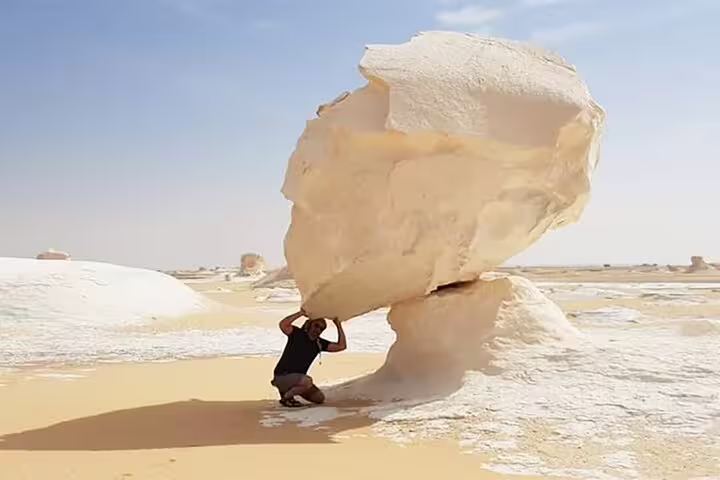 Traveler posing under mushroom rock in Egypt White Desert on private 4-day Bahariya Oasis safari tour