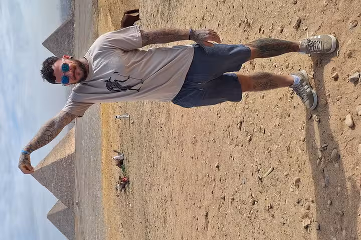 Traveler posing creatively with the majestic Pyramids of Giza, capturing a fun moment on a Cairo highlights tour.