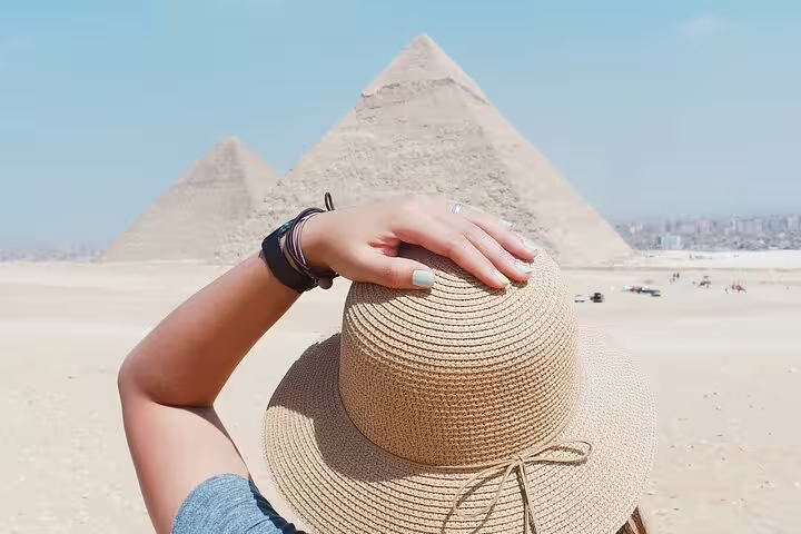 Traveler holding straw hat with Pyramids of Giza view, Cairo photo session add-on tour for Instagram shots