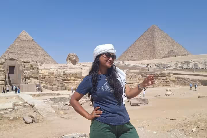 Traveler poses joyfully with iconic pyramids and Sphinx at Giza, highlighting Egypt's ancient wonders on guided tour.