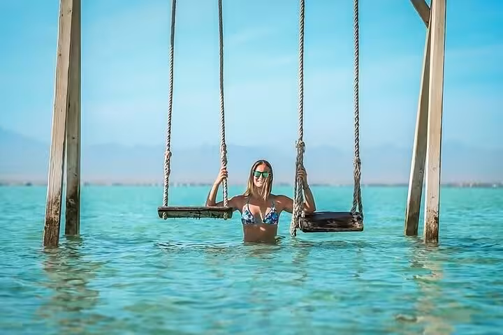 Traveler on sea swing in turquoise Red Sea water during Hula Hula Island trip from Hurghada with lunch