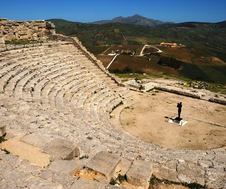 Traveler standing in the ancient Segesta Greek theatre near Palermo, overlooking rolling Sicilian hills on a private tour