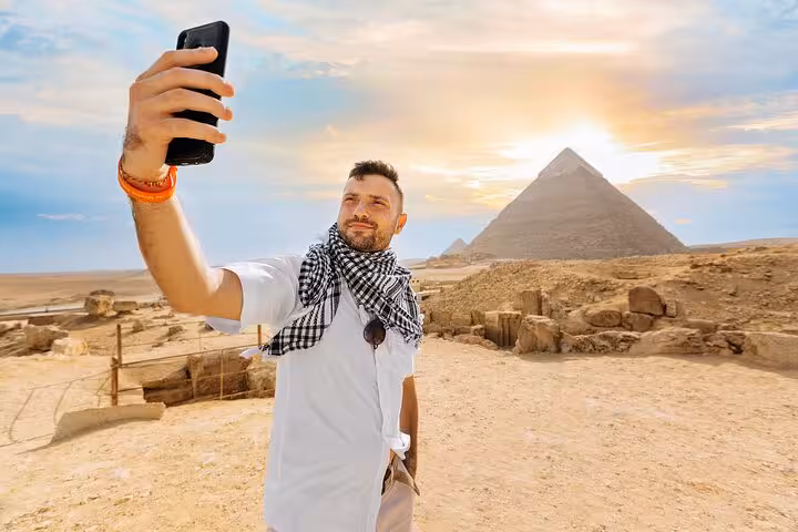 Traveler taking a selfie at the Great Pyramids of Giza on a full-day Cairo tour from Sharm by bus