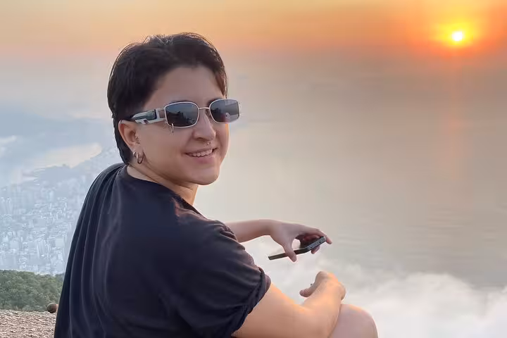 Smiling traveler watching sunrise over the ocean, capturing the moment during Sunrise Walk Two Brothers tour.