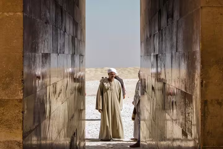 Travelers in a stone corridor at Saqqara necropolis, Egypt, on a guided royal expedition to Giza and Dahshur