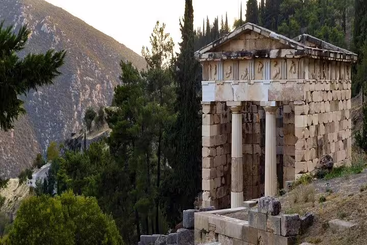Treasury of the Athenians in Delphi with mountain views, scenic stop on a private full-day tour from Athens