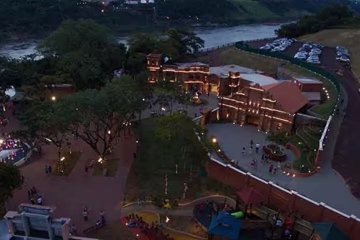 Twilight aerial view of illuminated Tres Fronteiras Landmark with scenic river backdrop.