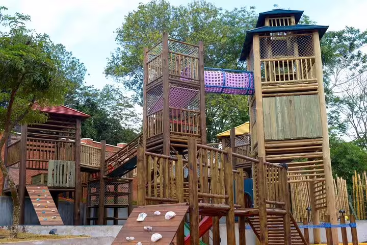 Wooden playground structures surrounded by lush greenery at Tres Fronteiras Landmark.
