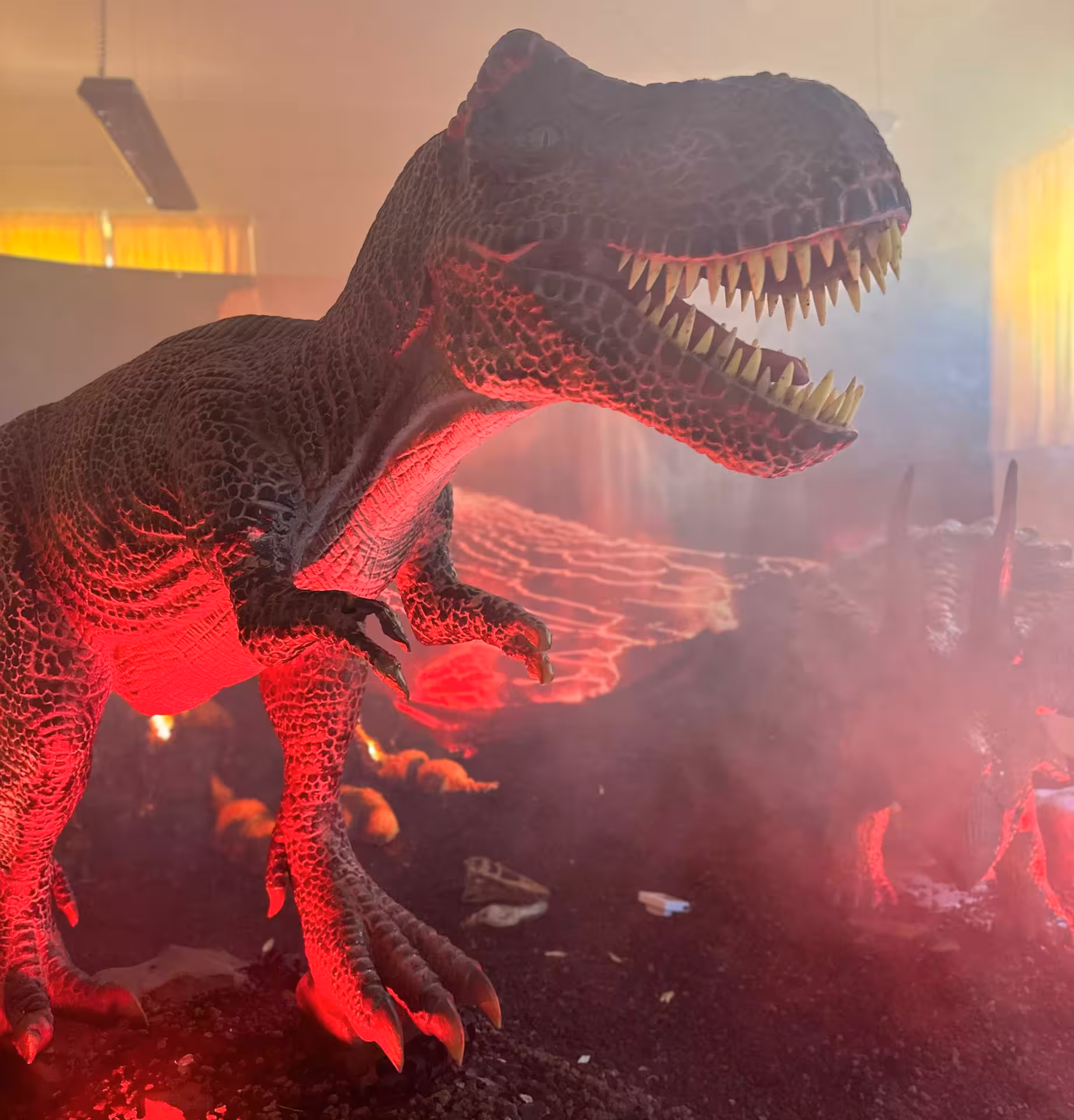 Experience a roaring T-Rex exhibit at Porto Conte Park in Alghero, with dramatic red lighting and mist effects.