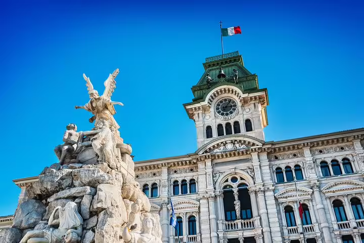 Close-up of Trieste’s Palazzo del Municipio clocktower and ornate fountain under clear blue sky on a guided hidden gems tour